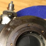 Close up of the flash sync post and aperture band guide. The flash sync post is riveted through the original hole the aperture band guide was mounted via.